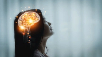 Profile view of a woman with a glowing brain illustration above her head, representing mental activity.